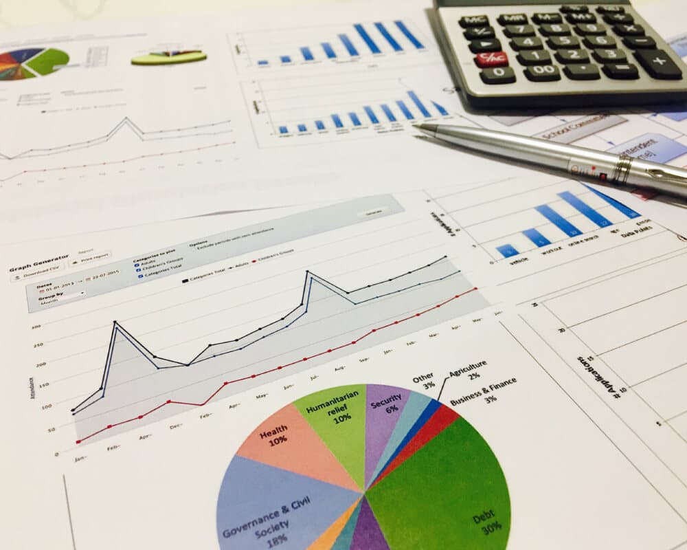 Reportes impresos con gráficos de tendencia y una calculadora sobre un escritorio