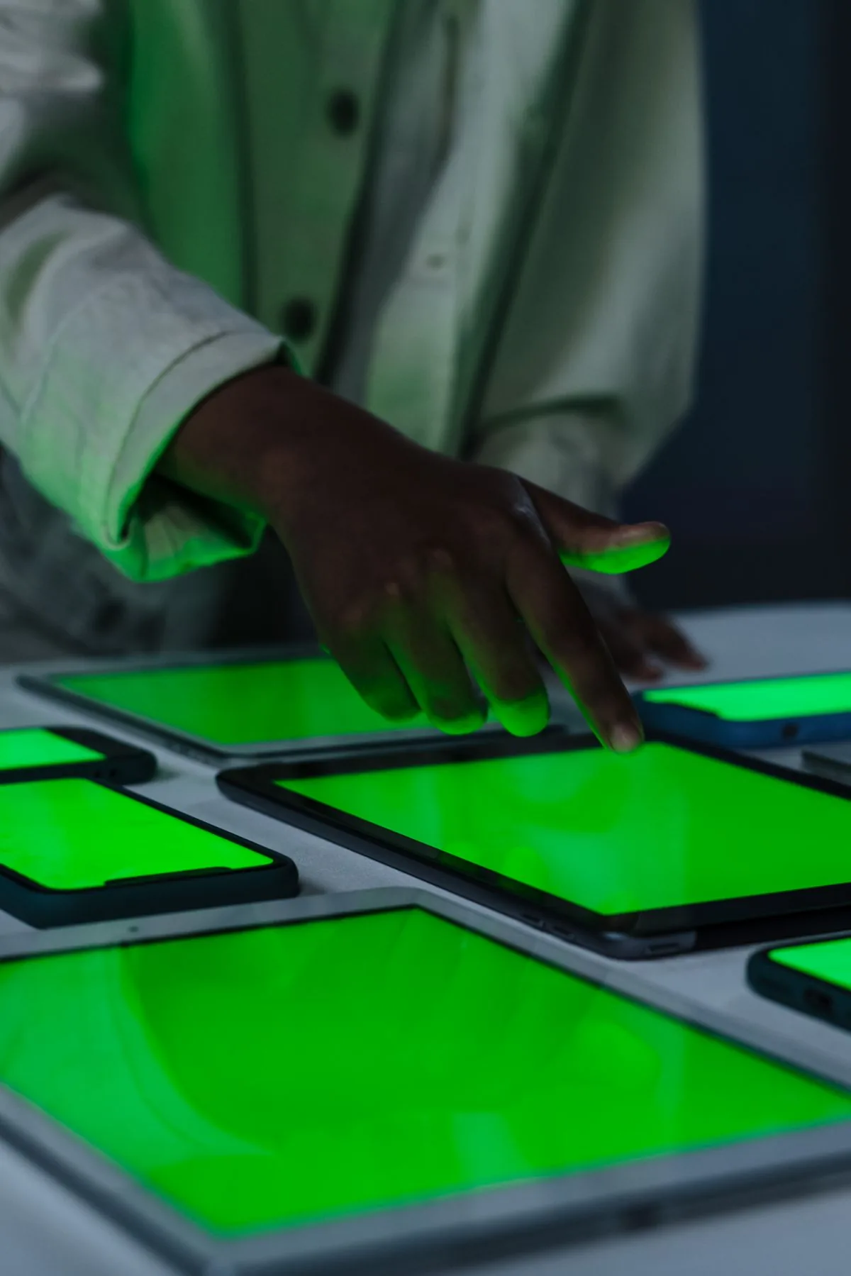 Mano tocando una pantalla iluminada entre varios dispositivos sobre una mesa, representando procesos comerciales automatizados