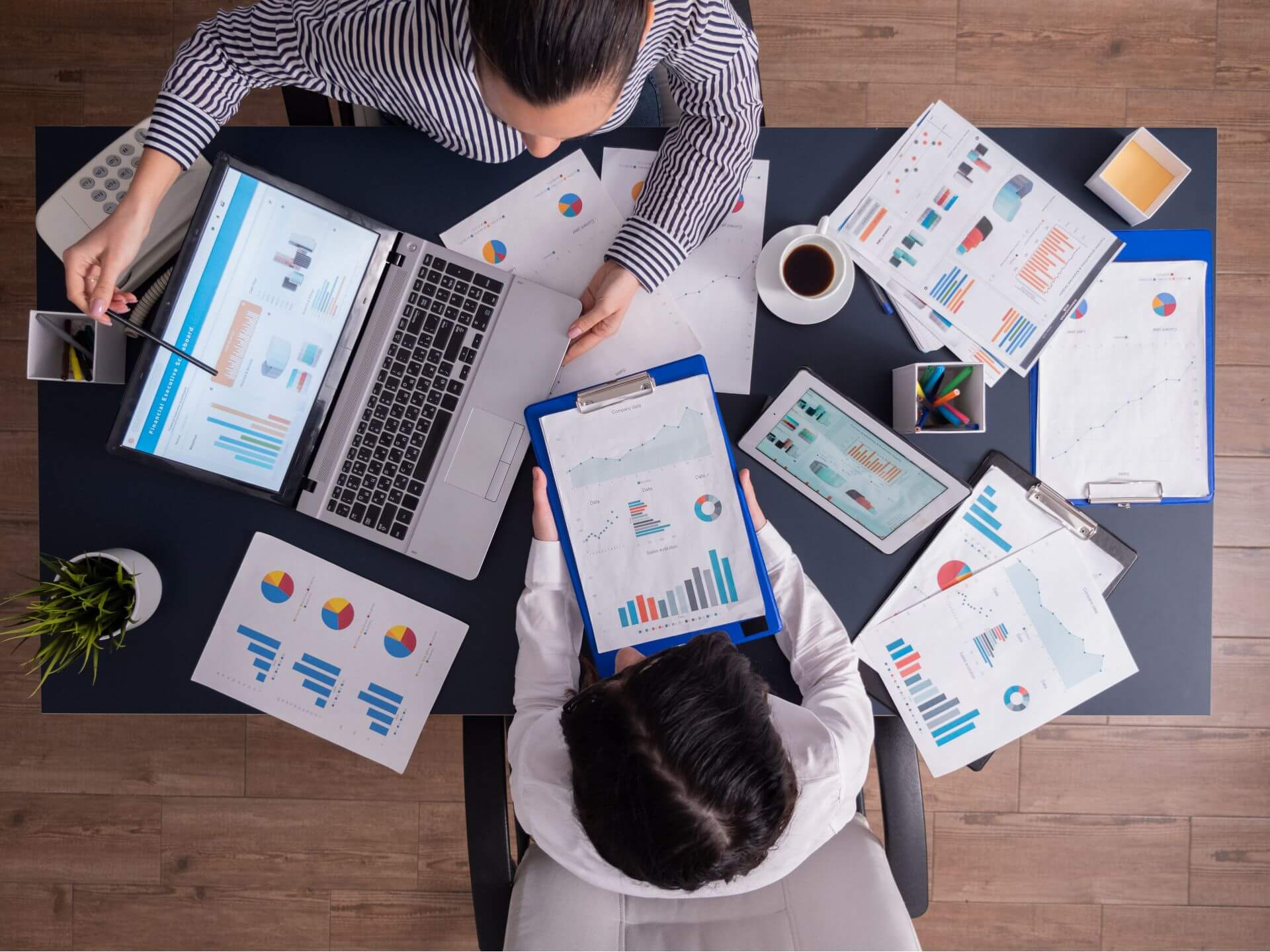 Vista superior de un escritorio de oficina con laptop, gráficos impresos y un tablero de métricas de marketing